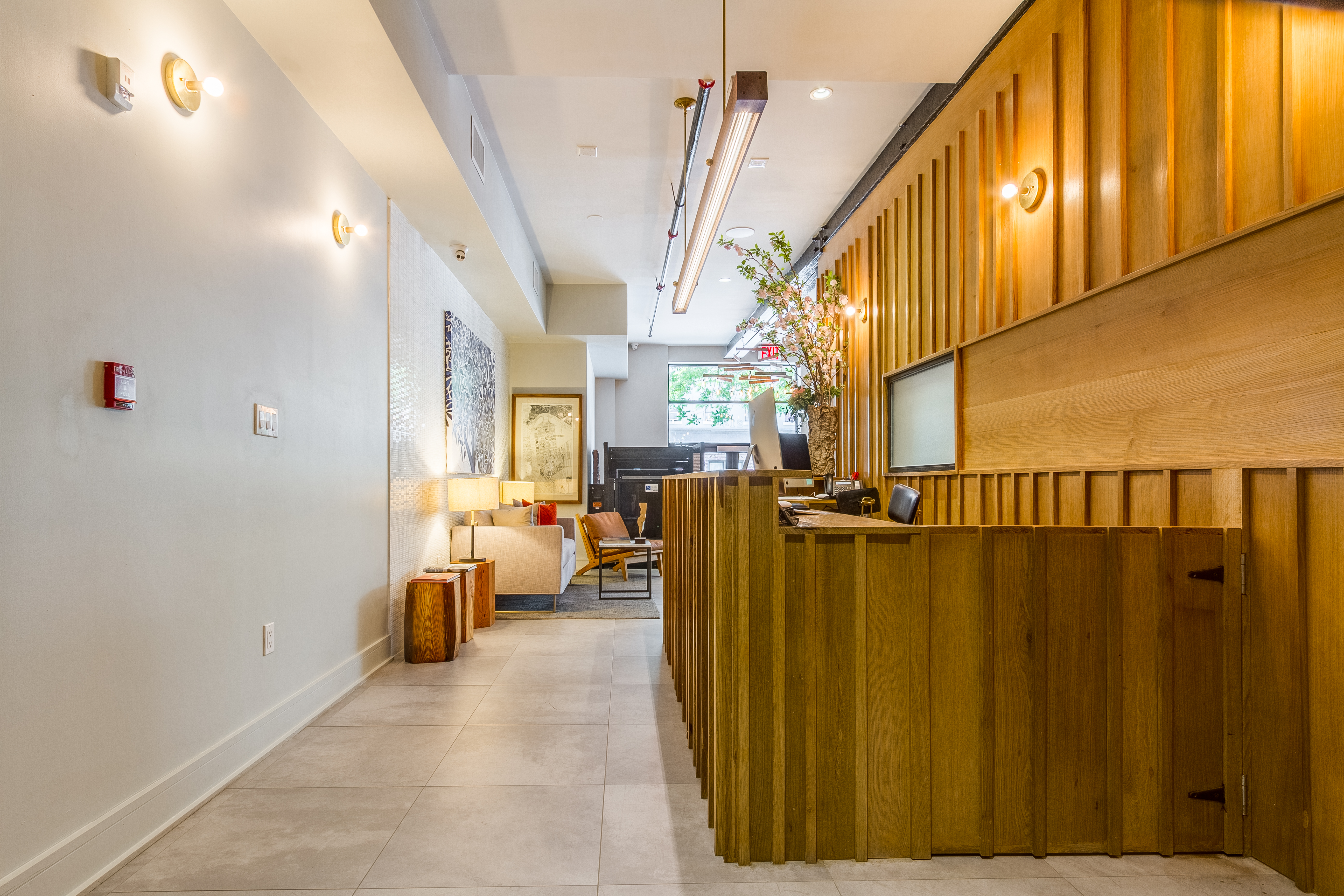 A modern lobby with a wooden reception desk, seating area, and lighting.